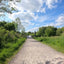 Breiter Schotterweg zwischen Wiesen und Bäumen unter blauem Himmel bei Saarbrücken