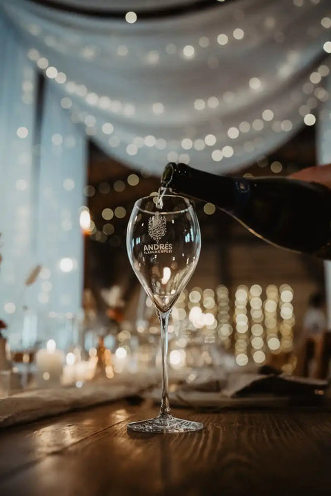 Sekt wird beim Sektempfang in ein Glas mit dem Logo von Andrés Flaschenpost eingeschenkt