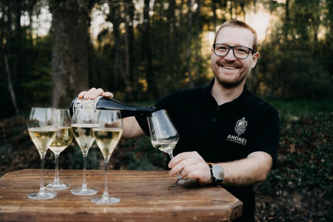 André schenkt bei einer privaten Weinprobe Weißwein in Gläser ein