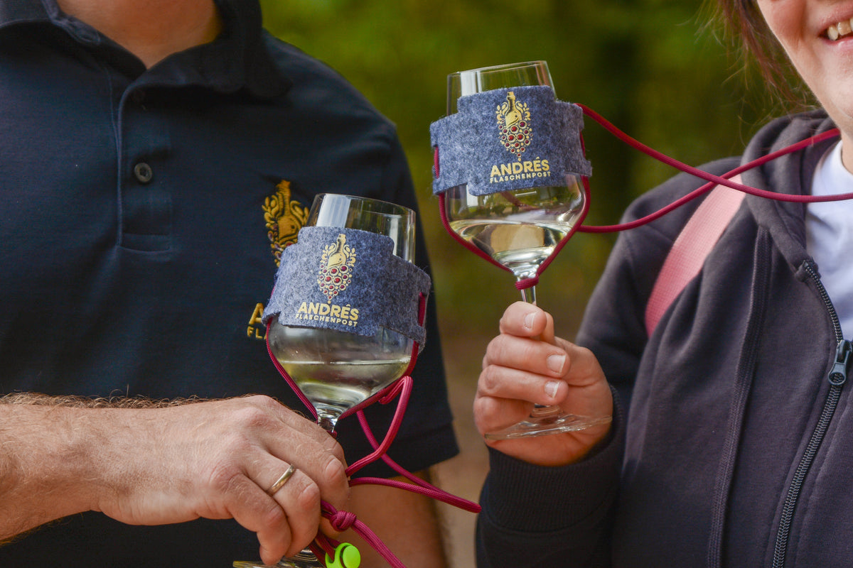 Drei Gläser Weißwein und eine Flasche auf einem Holztisch im Wald