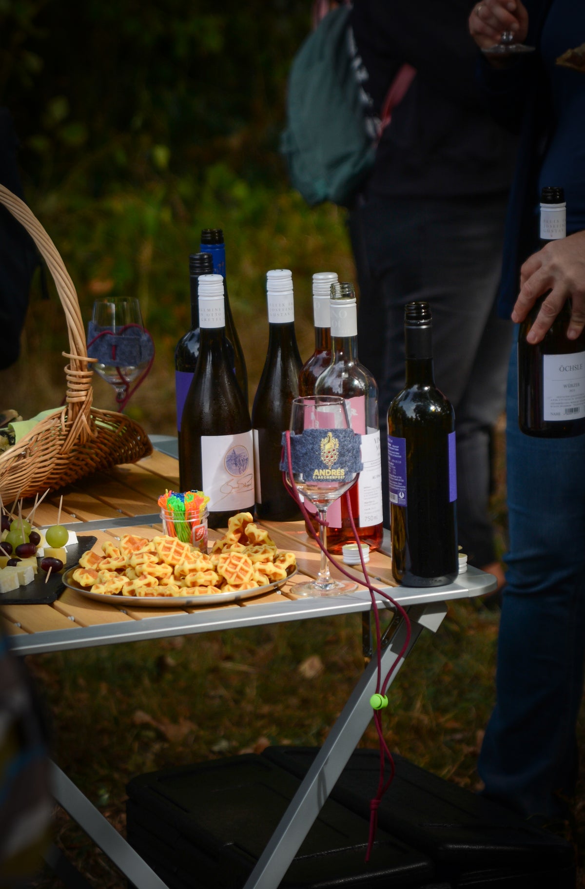 Weinflaschen und Snacks auf einem Klapptisch in der Abenddämmerung