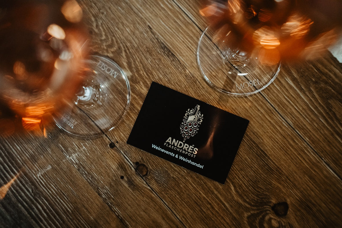 Karte von Andrés Flaschenpost zwischen zwei Gläsern Roséwein auf einem Holztisch