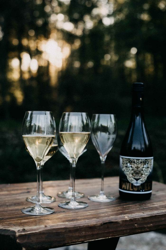 Sekt wird beim Sektempfang in ein Glas mit dem Logo von Andrés Flaschenpost eingeschenkt