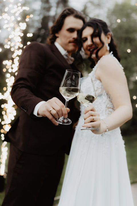 Brautpaar stößt bei der Hochzeit mit zwei Weingläsern an