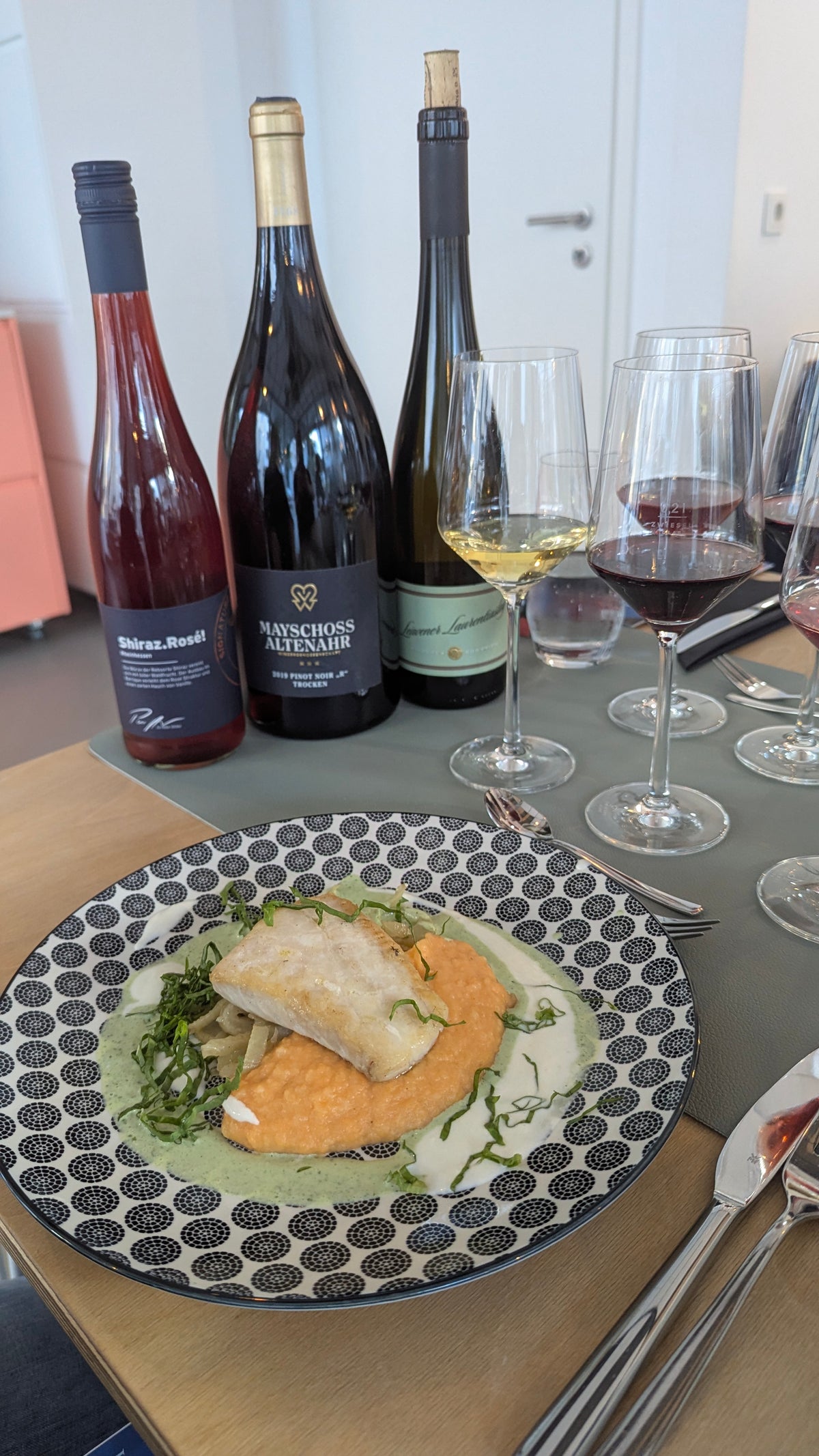 Rotwein und Weißwein in Verkostungsgläsern auf einem gedeckten Tisch